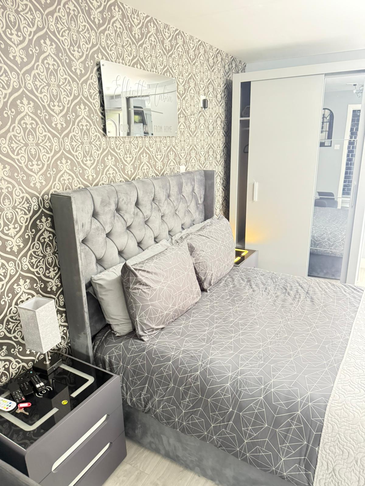 The elegant bedroom at Elliott's Cabin with a plush grey velvet bed and mirror